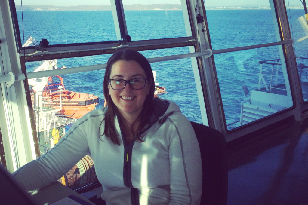 A woman sitting inside a boat by a large window