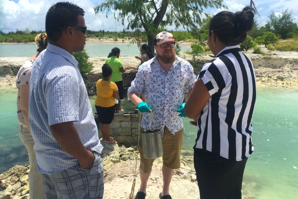 a man talking to a group of people next to ponds