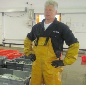 Photo of man in fishing gear at a fish market