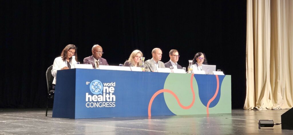 6 people sitting at a table on the stage to take part in the panel