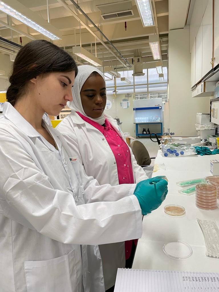 2 women in lab coats standing by a lab bench