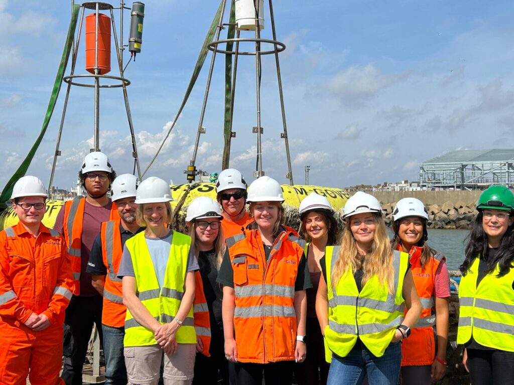 group of people wearing high vis and hard hats next to the sea