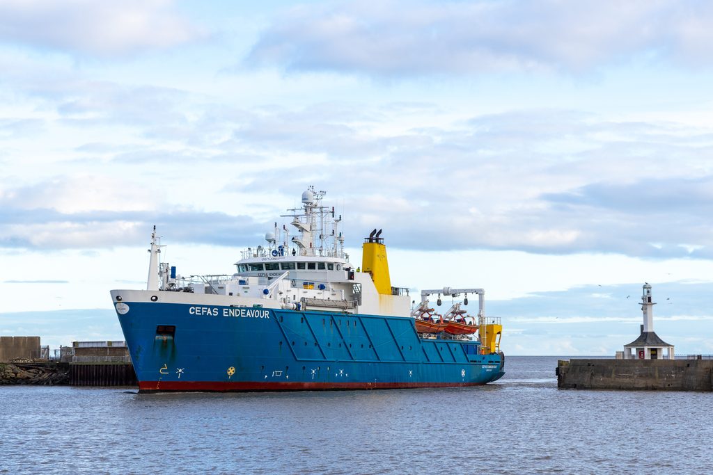 blue ship sailing between harbour walls