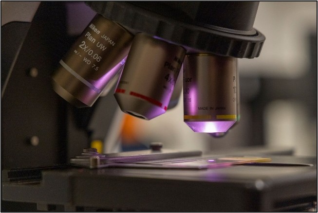 close up of microscope lenses and slide with purple lights